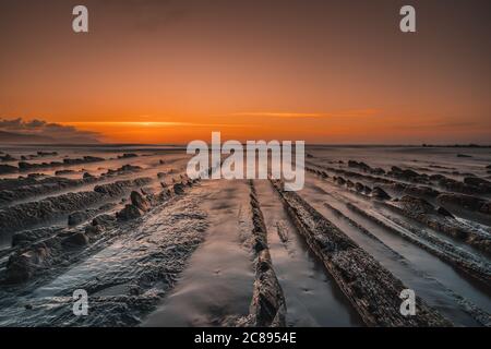 Blick auf den wunderschönen orangen Sonnenuntergang auf dem Flysch Der Strand von Sakoneta Stockfoto