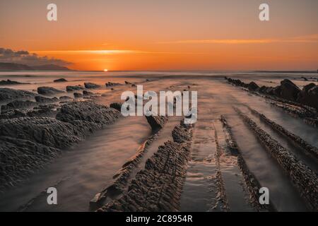 Blick auf den wunderschönen orangen Sonnenuntergang auf dem Flysch Der Strand von Sakoneta Stockfoto