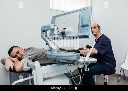 Arzt, der einen Ultraschalluntersuchung an einem Patienten durchführt, der auf einer Bahre liegt Stockfoto