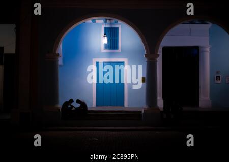 Zwei junge kubanische Jungen spielen nachts Schach vor einem blauen Gebäude, Havanna, Kuba Stockfoto