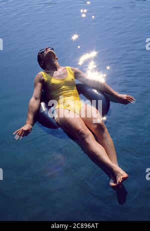 Eine junge Schwimmerin, die in einem inneren Rohr auf einem Teich in den Pocono Mountains in Pennsylvania schwimmt.