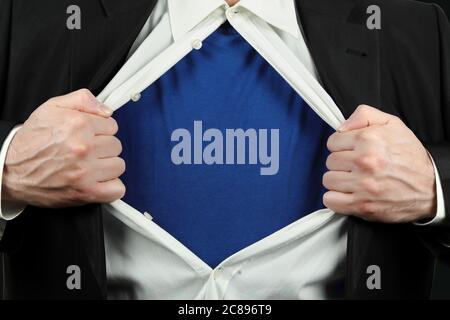 Geschäftsmann öffnet sein Hemd, um leere blaue T-Shirt für Hintergründe zu offenbaren Stockfoto