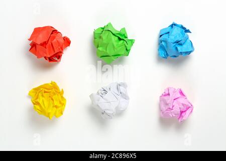 Sechs bunte zerknitterte Papierkugeln auf weißer Oberfläche Stockfoto