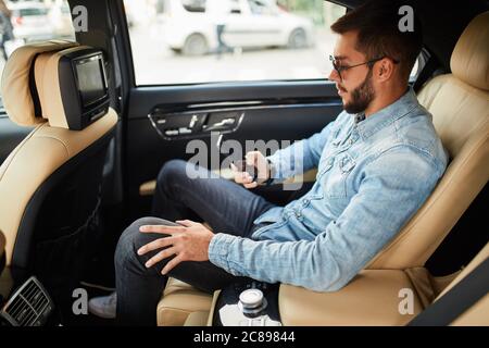 Schöner Mann wird einen Anruf zu machen. Seitenansicht Foto. Internet. Mann schaut auf das Telefon. Kerl, der Musik, Bilder. Filme herunterlädt Stockfoto