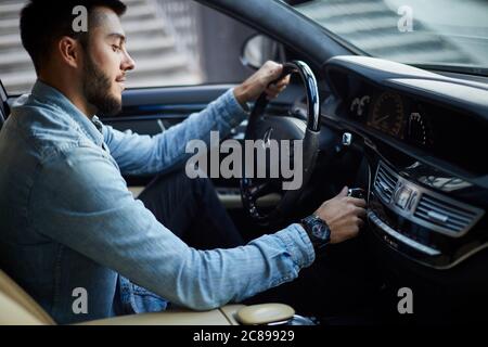 Junge aktive Mann beginnt Reisen. Ehrfürchtige Mann Betätigen einer Maschine Seitenansicht Foto Stockfoto