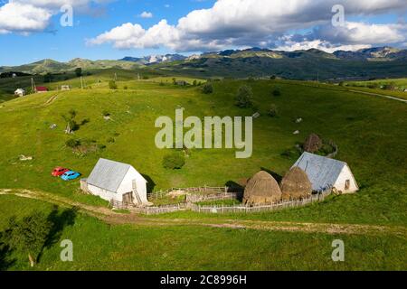 Luftaufnahme der ländlichen Landschaft - Heuballen, Holzzäune, Schotterstraße und Häuser auf einer Wiese, Nationalpark Durmitor, Montenegro Stockfoto