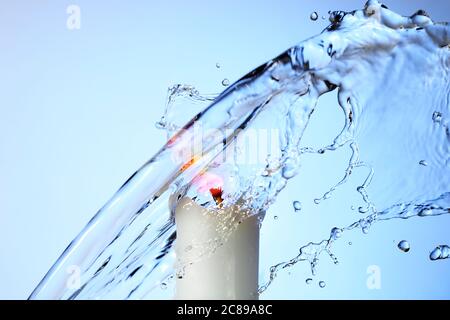 Wasser spritzt auf brennende Kerze gegen blauen Gradienten, abstrakte High-Speed-Fotografie Stockfoto