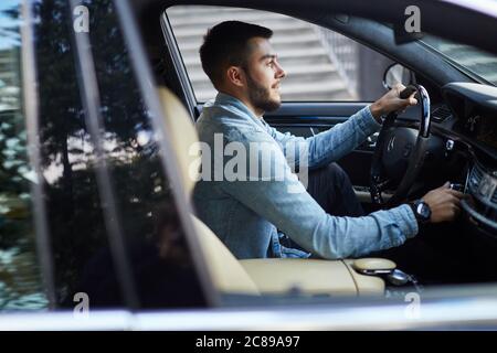 Seitenansicht abgeschnitten Schuss. Junge Mann startet das Auto. Student bestandene Prüfungen, um einen Führerschein zu bekommen Stockfoto