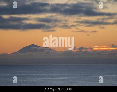 Wunderschöner orangefarbener Sonnenaufgang über dem ruhigen Meer und dem Pico del Teide auf Teneriffa von La Palma aus gesehen Stockfoto