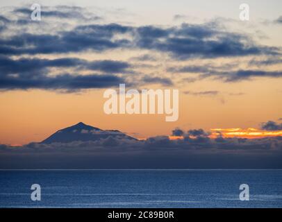 Wunderschöner orangefarbener Sonnenaufgang über dem ruhigen Meer und dem Pico del Teide auf Teneriffa von La Palma aus gesehen Stockfoto