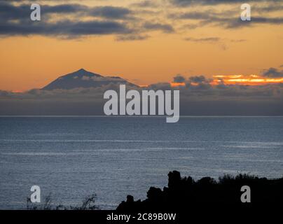 Wunderschöner orangefarbener Sonnenaufgang über dem ruhigen Meer und dem Pico del Teide auf Teneriffa von La Palma aus gesehen Stockfoto