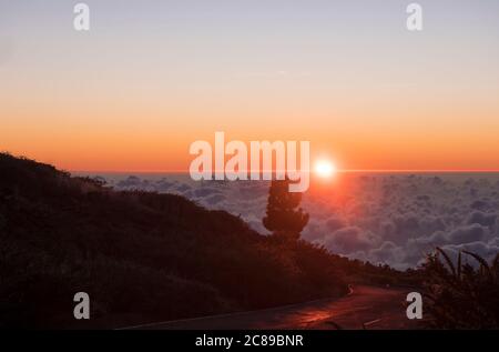 Schöner roter Sonnenuntergang über weißen Wolken über asphaltierten Straßen über Bergen bei La Palma, Kanarische Inseln, Spanien Stockfoto