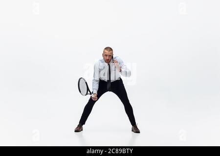 Zeit für Bewegung. Mann in Bürokleidung spielt Tennis isoliert auf weißem Studio Hintergrund. Geschäftsmann Ausbildung in Bewegung, Aktion. Ungewöhnliche suchen für Sportler, neue Aktivität. Sport, gesunder Lebensstil. Stockfoto