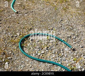 Zwei Enden der abgeklemmten, unterschiedlich farbigen grünen Wasserschläuche, die auf dem Boden liegen Stockfoto