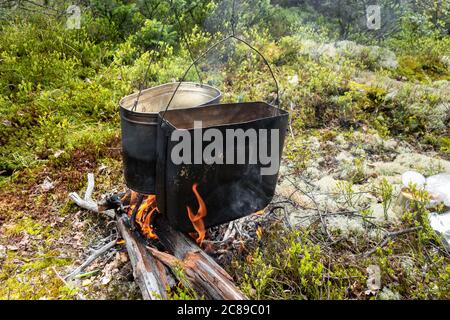 Das Kochen der Nahrung in den Bedingungen des Feldes, in den geräucherten Kessel über dem Feuer im Wald in der Lichtung. Das Konzept von Familienreisen und Erholung im Freien. Stockfoto