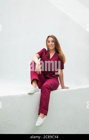 Medizinstudenten in burgunderroten OP-Anzügen stehen vor der Krankenpflegeschule. Junge Mädchen Gynäkologen Arzt. Stockfoto