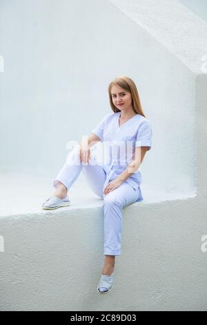 Medizinstudenten in burgunderroten OP-Anzügen stehen vor der Krankenpflegeschule. Junge Mädchen Kosmetik Arzt. Stockfoto