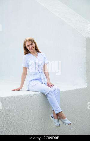 Medizinstudenten in burgunderroten OP-Anzügen stehen vor der Krankenpflegeschule. Junge Mädchen Kinderarzt Arzt. Stockfoto