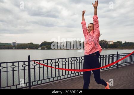 Mädchen Läufer beendet das Rennen mit einem roten Band. Stockfoto