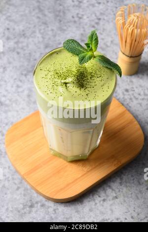 Glas Dalgona Eistee Matcha Tee und Bambus auf grau. Stockfoto