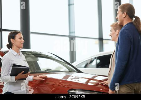 Vertriebsmitarbeiter erzählt vom Rabattprogramm und steht vor dem Geschäftspartner im Autohaus. Stockfoto