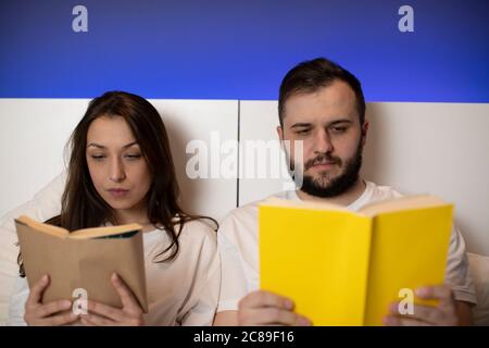 Ein paar Liebhaber tragen weiße Schlafanzug auf Bücher im Bett zu lesen konzentriert Stockfoto
