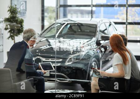 Portrait von zwei Autokäufer lesen Kaufvertrag und Unterzeichnung einer Kfz-Versicherung Papiere ein Auto mit einem Autokredit im Showroom zu kaufen. Stockfoto