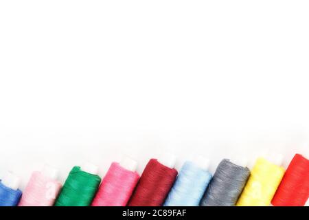 Nähfäden in verschiedenen Farben auf Rollen auf weißem Hintergrund. Freier Speicherplatz, Nahaufnahme. Isolieren Stockfoto