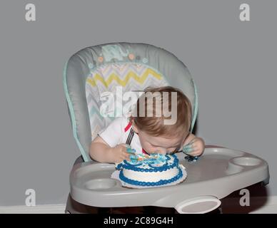 Kleinkind taucht Gesicht zuerst in eine zerschlagenen Kuchen an seinem ersten Geburtstag. Stockfoto