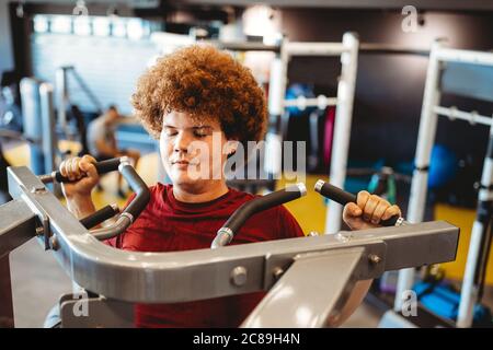Übergewichtiger junger Mann, der in der Sporthalle trainiert, um Ziele zu erreichen Stockfoto
