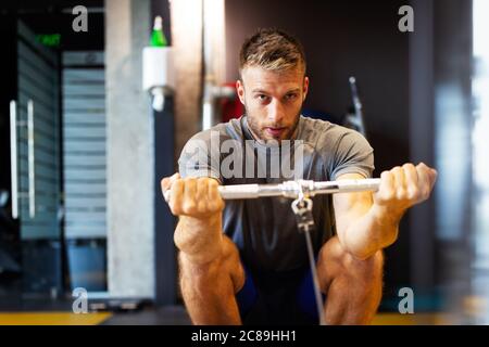 Fit Happy man trainiert im Fitnessstudio an einer Maschine Stockfoto