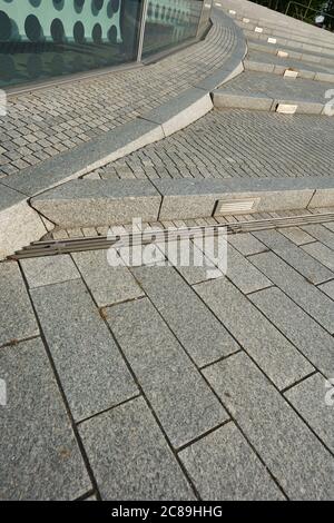 Graue Stufe aus Steinpflaster, Beleuchtung ist in den Kaskaden installiert, an der Seite eines Gebäudes, kaltes Bild in den frühen Morgen wenig Licht. Germa Stockfoto