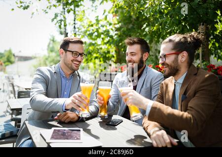 Junge Geschäftsleute trinken Bier, reden und lächeln, während sie sich in der Kneipe ausruhen Stockfoto