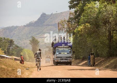 Lastwagen fahren auf steilen Mt. Elgon Bergstraßen voll mit Passagieren und landwirtschaftlichen Produkten in Bulambuli Dist., Uganda, Afrika. Stockfoto