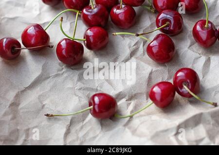 Beeren von reifen Kirschen auf einem Hintergrund von Bastelpapier. Selektiver Fokus. Nahaufnahme. Stockfoto
