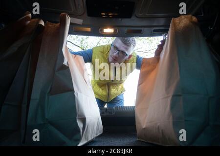 Delivery man Putting Einkaufspapier Taschen in Auto-Kofferraum Kurier Versand Konzept Stockfoto