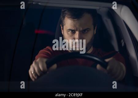 Junger bärtiger Mann fährt mit hoher Geschwindigkeit und hält das Lenkrad mit den Händen Stockfoto