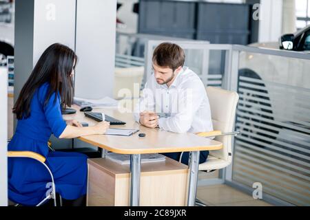 Geschäftsfrau, die vor dem Kauf eines Autos Versicherungsunterlagen unterschreibt, Stockfoto