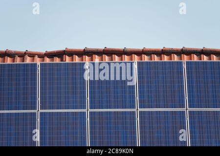 Blaue Sonnenkollektoren auf dem Dach der Hüte mit roten Ziegelsteinen, grauer Himmel. Deutschland Stockfoto