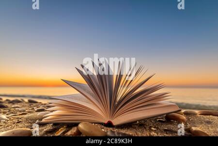 Gelassenheit am Strand. Buchen Sie am Strand mit weißen Kieselsteinen bei einem Sonnenaufgang. Stockfoto