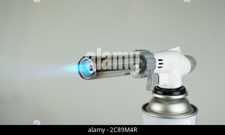 Gasbrenner mit blauer Feuerflamme auf grauem Hintergrund Stockfoto