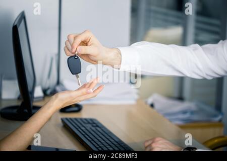 Beschnittene Ansicht des Mannes, der den Schlüssel übergab, und der Frau, die die Hände erhielt. Ihr Wunschkonzept Stockfoto