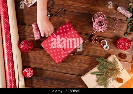 Weihnachtsgeschenke verpackt in rotem Papier mit hausgemachten Dekoration auf Holz- Hintergrund mit Dekor Elemente und Einheiten Stockfoto