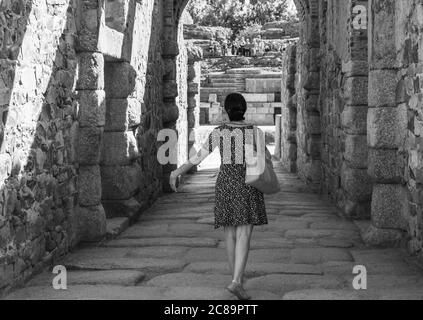 Frau mit dem Rücken, die durch einen Steinkorridor zum römischen Amphitheater in Mérida vorrückte, als wäre sie eine Schauspielerin oder Tänzerin, die auf die Bühne geht Stockfoto