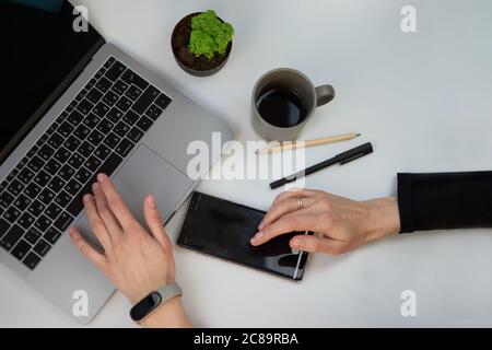 Weißer Büroschreibtisch von oben mit leerem Notebook, Laptop-Tastatur, Stift, Pflanzen und anderen Büromaterialien. Kaffeetasse mit Kopierfläche, flach Stockfoto