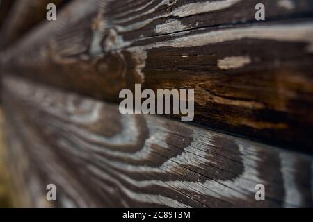 Rustikale Textur an der Wand im Freien, Seitenansicht, dunkler Hintergrund. Selektiver Fokus von braunen alten Volumen rauen Holzplanken, erstaunliche natürliche Muster für Design und Dekoration. Konzept der natürlichen Einrichtung. Stockfoto