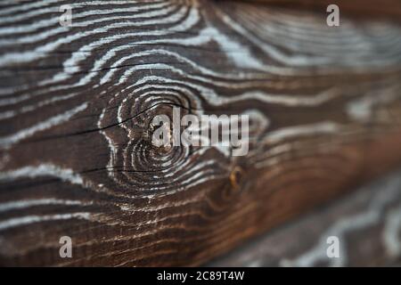 Rustikale Textur an der Wand im Freien, Seitenansicht, dunkler Hintergrund. Selektiver Fokus von braunen alten Volumen rauen Holzplanken, erstaunliche natürliche Muster für Design und Dekoration. Konzept der natürlichen Einrichtung. Stockfoto