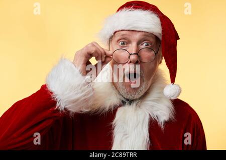 Porträt von gealterten überrascht Bug-eyed erstaunt Weihnachtsmann mit weit offenen Augen, Mund, Anpassung Augenabnutzung, schockiert, dass Eltern nicht noch b Stockfoto