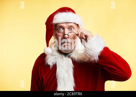 Porträt von gealterten überrascht Bug-eyed erstaunt Weihnachtsmann mit weit offenen Augen, Mund, Anpassung Augenabnutzung, schockiert, dass Eltern nicht noch b Stockfoto