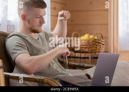 Der junge Mann nimmt an einem Treffen mit Kollegen Teil, das über einen Laptop aus der Ferne erfolgt. Stockfoto